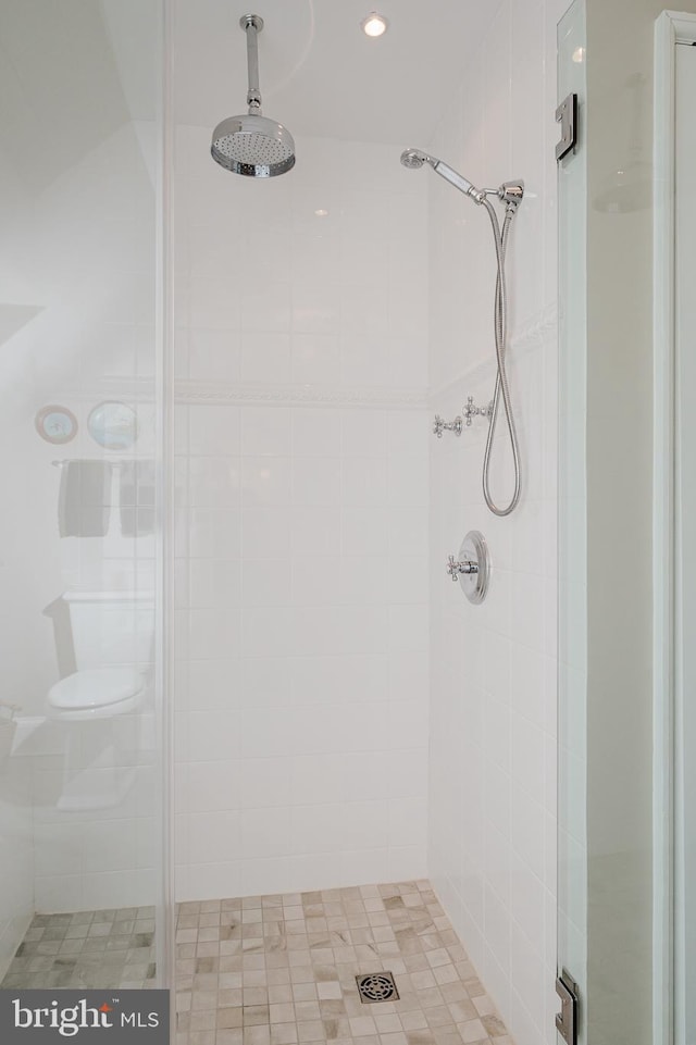 bathroom with a tile shower and toilet