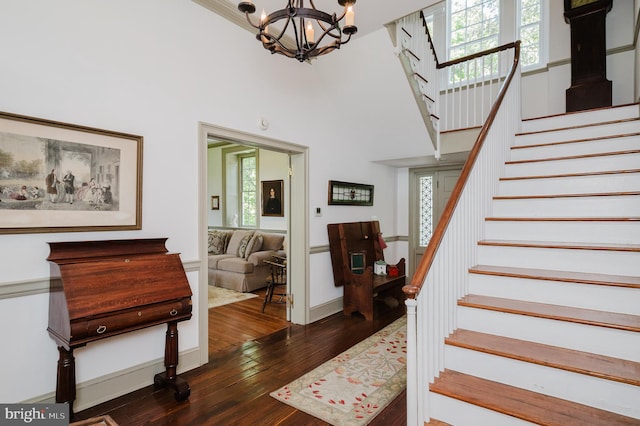 stairway featuring a notable chandelier, a towering ceiling, and dark hardwood / wood-style flooring