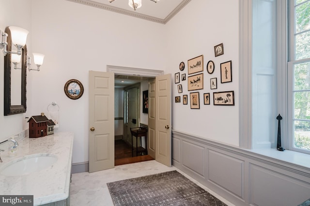 interior space with tile flooring, a healthy amount of sunlight, crown molding, and vanity