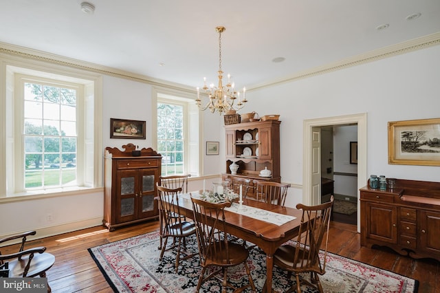 dining space with a notable chandelier, plenty of natural light, crown molding, and dark hardwood / wood-style flooring