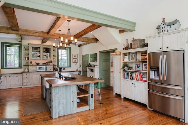 kitchen with hardwood / wood-style floors, an island with sink, pendant lighting, a healthy amount of sunlight, and appliances with stainless steel finishes