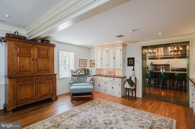 living area featuring beamed ceiling, crown molding, and wood-type flooring