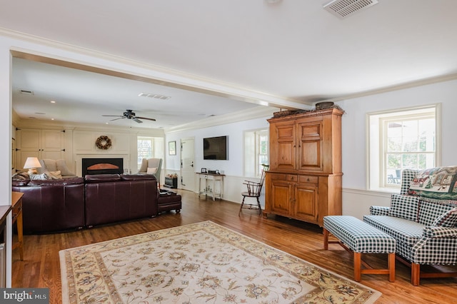 living room with ornamental molding, wood-type flooring, and ceiling fan