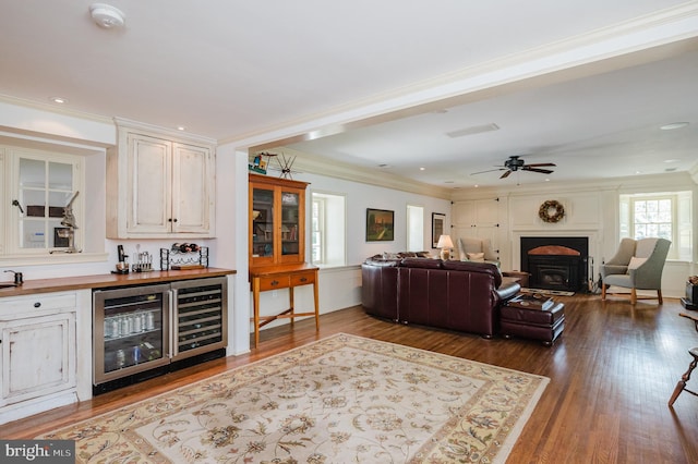 living room featuring hardwood / wood-style flooring, ornamental molding, ceiling fan, and wine cooler