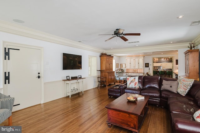 living room with hardwood / wood-style flooring, ornamental molding, and ceiling fan