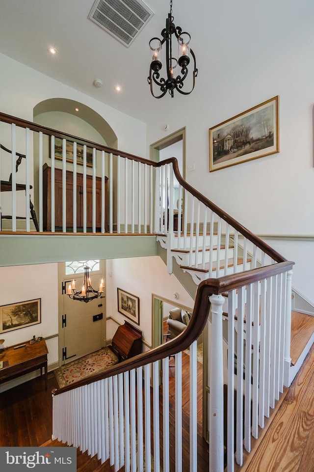 stairway with hardwood / wood-style floors and a chandelier