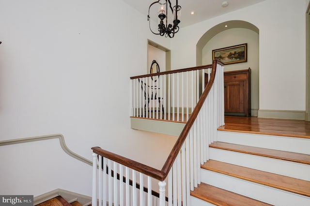 staircase with hardwood / wood-style flooring and a chandelier