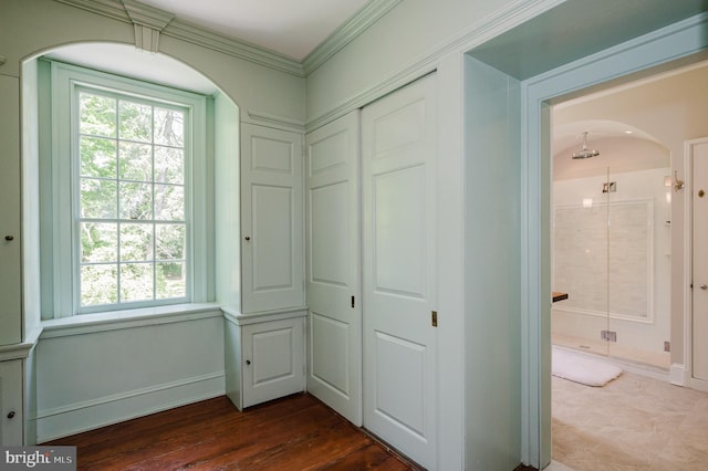 interior space with crown molding, multiple windows, a closet, and hardwood / wood-style floors