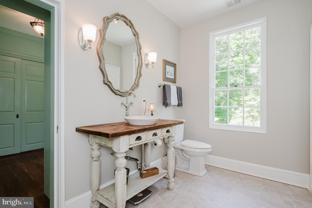 bathroom featuring hardwood / wood-style floors, vanity with extensive cabinet space, and toilet