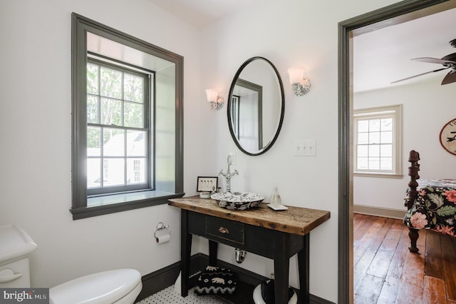 bathroom featuring ceiling fan, a healthy amount of sunlight, hardwood / wood-style floors, and toilet