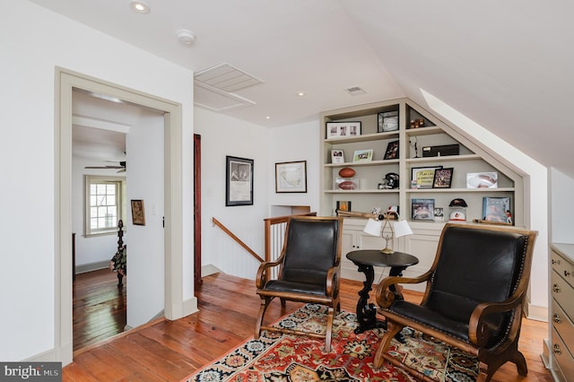 sitting room with light hardwood / wood-style floors, built in shelves, ceiling fan, and vaulted ceiling