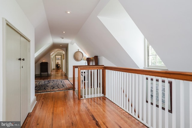 hall featuring wood-type flooring and vaulted ceiling