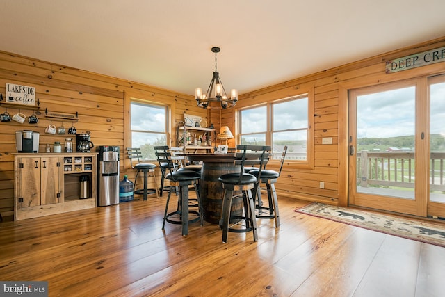 dining room featuring wood walls, light wood-type flooring, and plenty of natural light