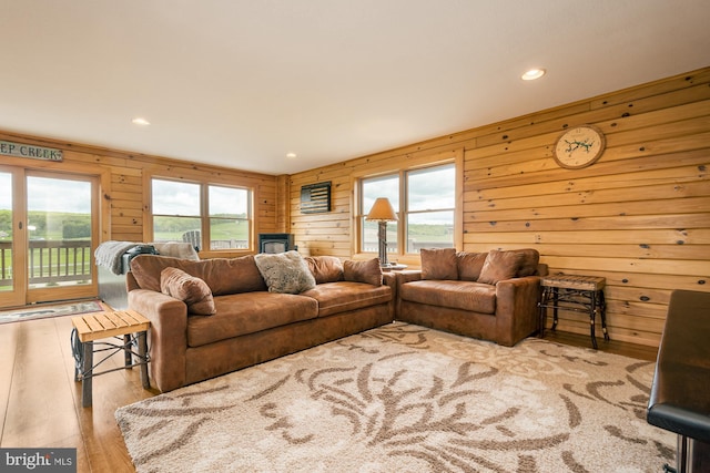 living room featuring wood walls, light wood-type flooring, and a wealth of natural light