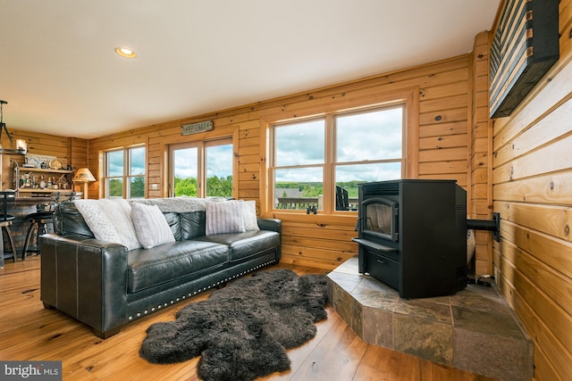 living room featuring wood walls, hardwood / wood-style flooring, a wood stove, and recessed lighting