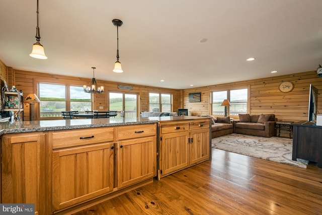 kitchen featuring wood walls, hardwood / wood-style floors, pendant lighting, and a wealth of natural light