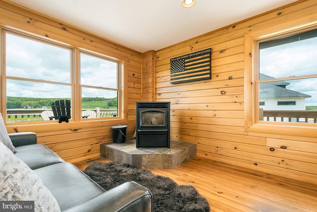 living area featuring a wood stove, wooden walls, and wood finished floors