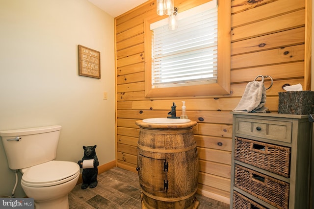 bathroom featuring toilet, wooden walls, wood finished floors, and vanity