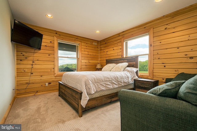 carpeted bedroom featuring wood walls and multiple windows