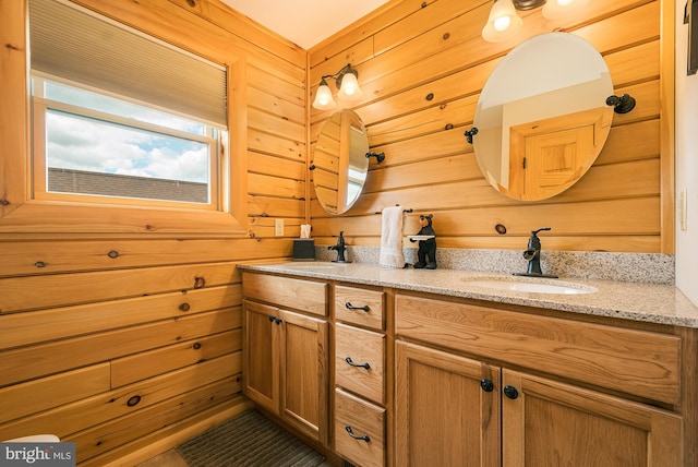 bathroom featuring dual bowl vanity and wood walls