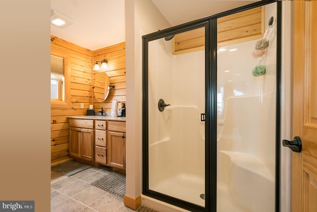 bathroom featuring wood walls, tile patterned flooring, a shower stall, and vanity