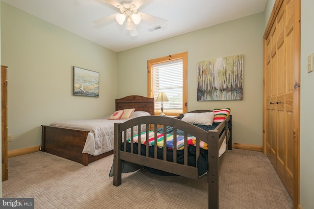 bedroom with ceiling fan, light colored carpet, and a closet