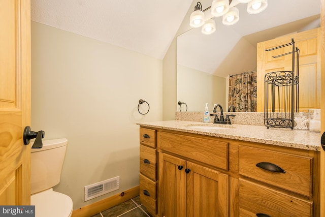 bathroom with toilet, vanity, vaulted ceiling, and tile patterned flooring