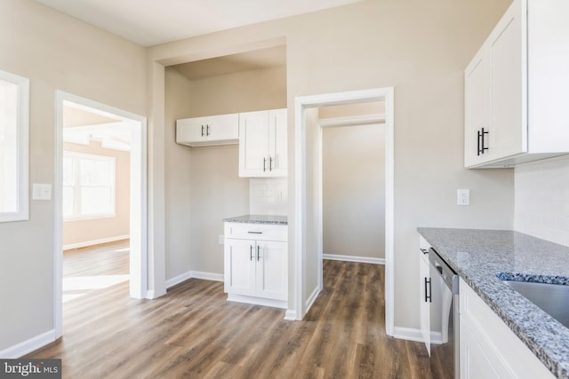 kitchen featuring white cabinetry, light stone countertops, stainless steel dishwasher, dark hardwood / wood-style flooring, and tasteful backsplash