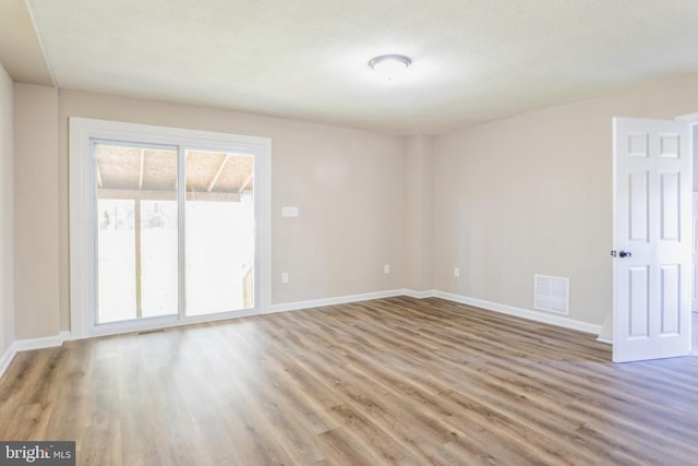 spare room featuring a healthy amount of sunlight and wood-type flooring