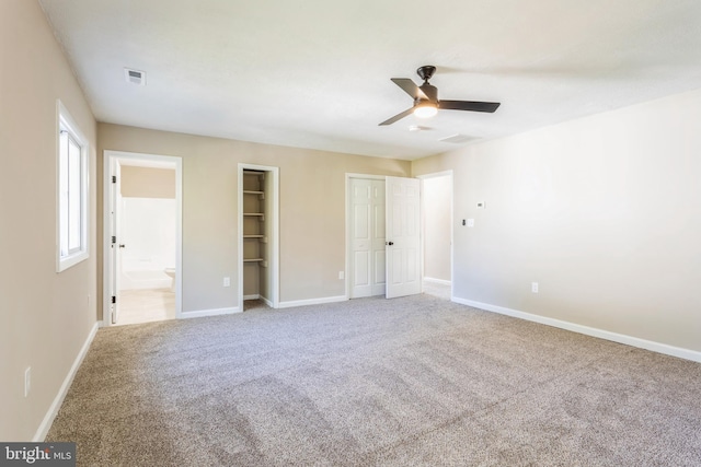 unfurnished bedroom featuring two closets, carpet, ceiling fan, and ensuite bath