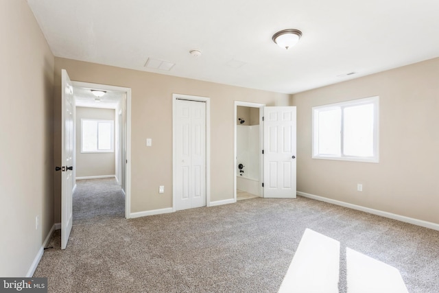 unfurnished bedroom with ensuite bath and carpet floors