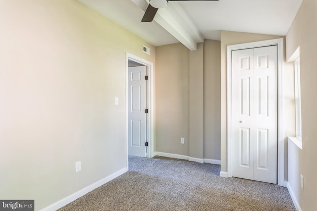 unfurnished bedroom with a closet, ceiling fan, vaulted ceiling, and carpet flooring