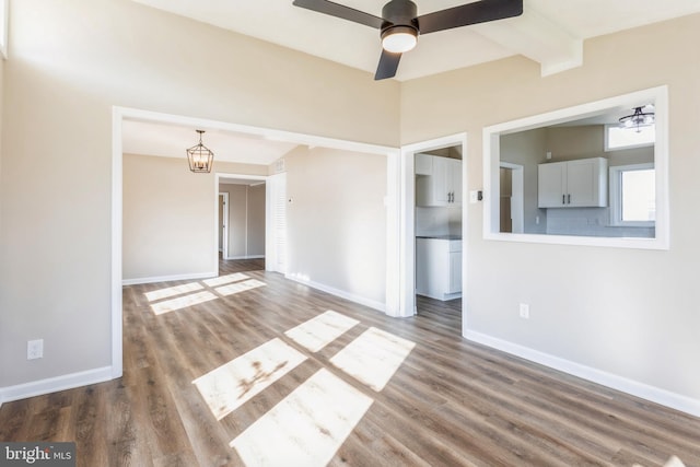 empty room featuring beam ceiling, wood-type flooring, and ceiling fan