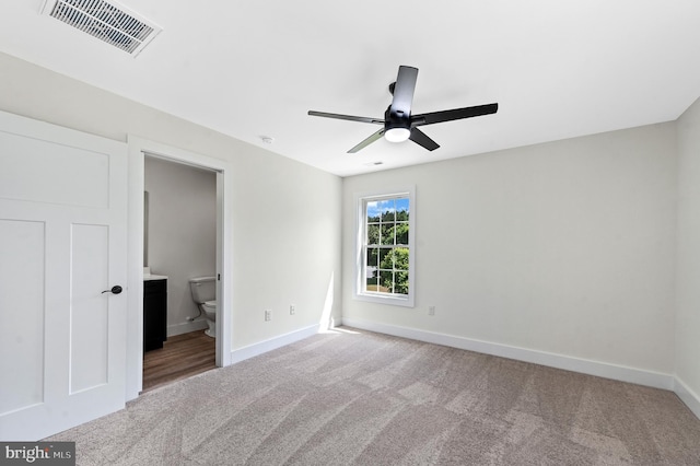 unfurnished bedroom with ensuite bath, ceiling fan, and light carpet