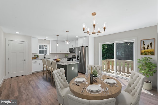 dining area featuring a chandelier, sink, and light hardwood / wood-style flooring