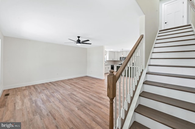 stairway featuring hardwood / wood-style floors and ceiling fan with notable chandelier