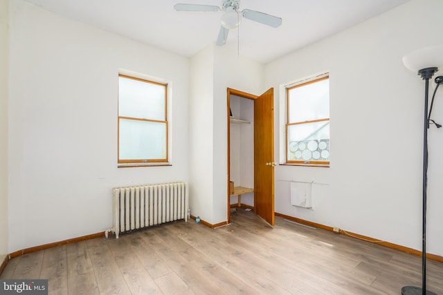 unfurnished bedroom with light hardwood / wood-style floors, a closet, radiator heating unit, and ceiling fan