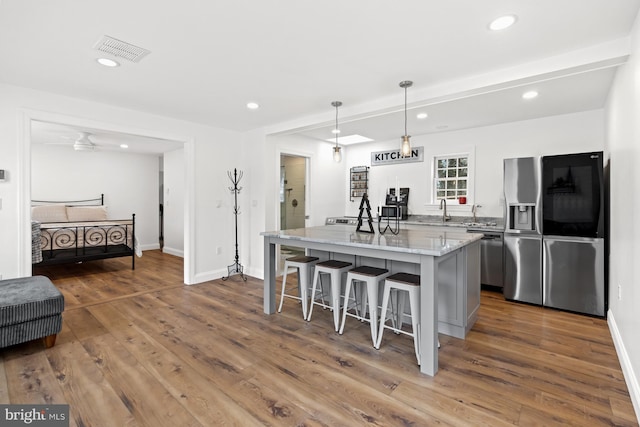 kitchen featuring decorative light fixtures, a center island, stainless steel appliances, and hardwood / wood-style flooring