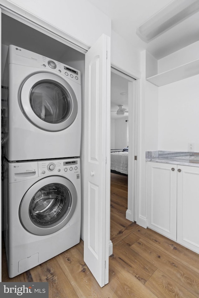 clothes washing area featuring light wood-type flooring and stacked washer / drying machine