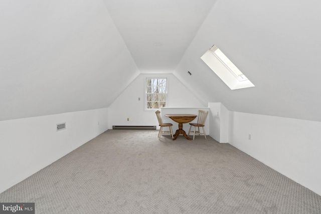 additional living space featuring vaulted ceiling with skylight, light colored carpet, and a baseboard heating unit