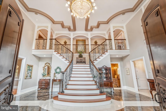 foyer entrance with a chandelier, a high ceiling, and crown molding