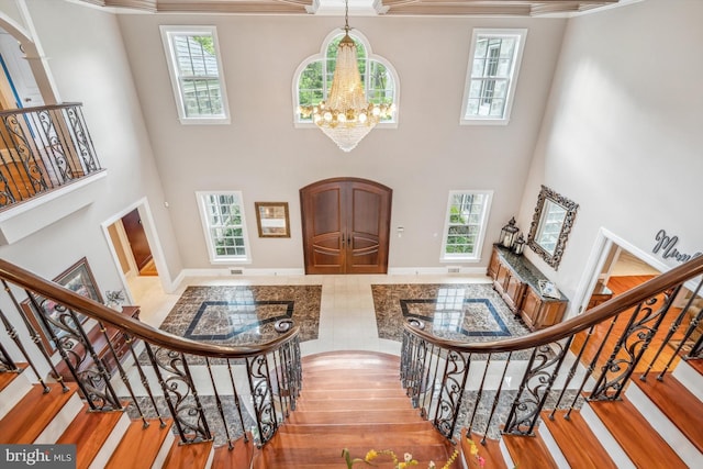 foyer featuring a chandelier, a healthy amount of sunlight, a high ceiling, and light hardwood / wood-style flooring