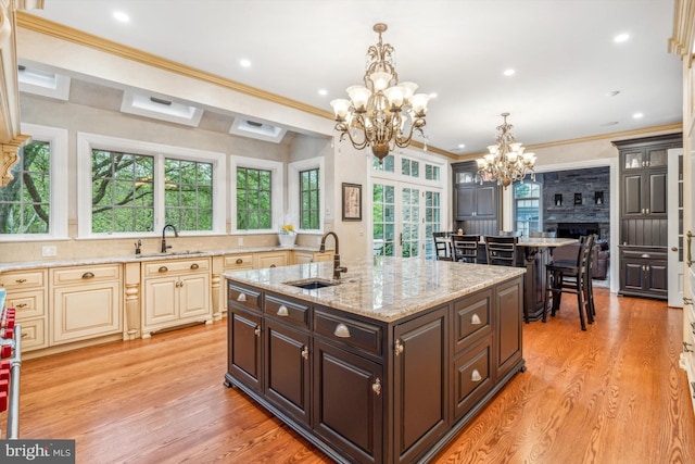 kitchen featuring a fireplace, crown molding, dark brown cabinetry, and sink