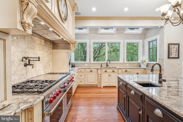 kitchen with cream cabinets, range with two ovens, sink, light wood-type flooring, and dark brown cabinets