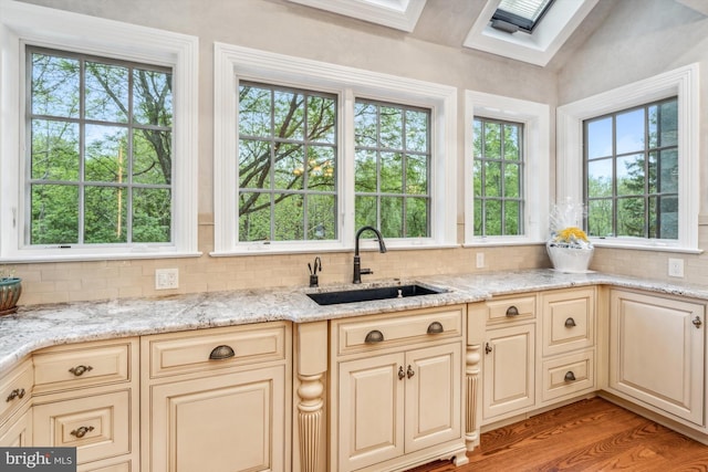 kitchen featuring backsplash, light stone counters, and sink