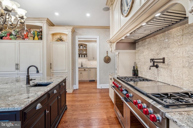 kitchen featuring light stone countertops, sink, double oven range, custom exhaust hood, and hardwood / wood-style flooring