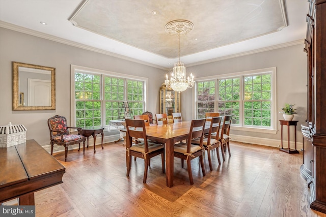 dining space with light hardwood / wood-style floors, a raised ceiling, and crown molding