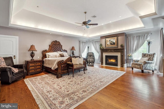 bedroom with a raised ceiling, ceiling fan, and hardwood / wood-style flooring