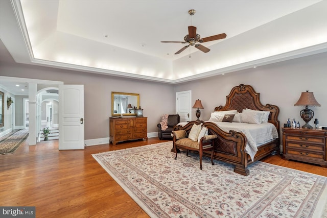 bedroom featuring a tray ceiling, light hardwood / wood-style flooring, and ceiling fan