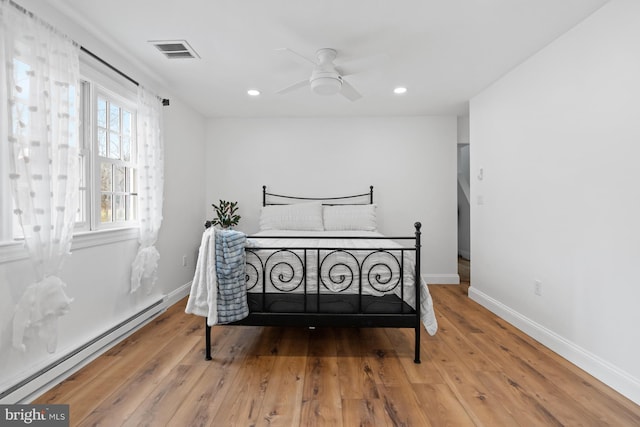 bedroom featuring ceiling fan, wood-type flooring, and a baseboard heating unit